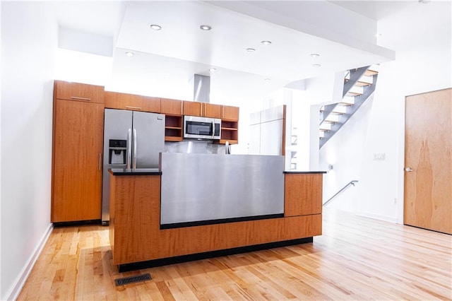 kitchen with a high ceiling, stainless steel appliances, and light wood-type flooring