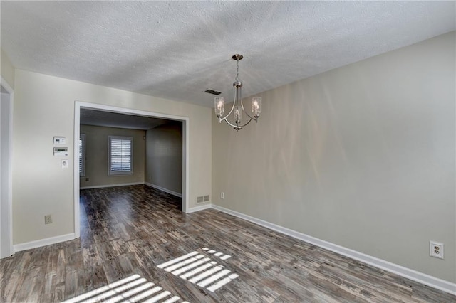 unfurnished dining area featuring a textured ceiling, dark hardwood / wood-style floors, and an inviting chandelier