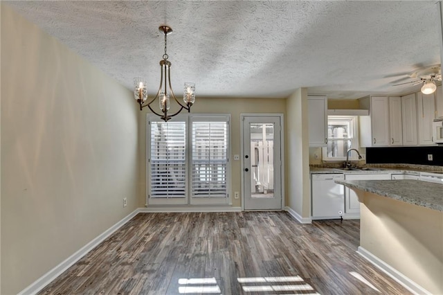 kitchen with ceiling fan with notable chandelier, white appliances, sink, pendant lighting, and white cabinetry