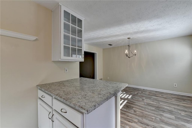 kitchen featuring light stone counters, a notable chandelier, pendant lighting, a textured ceiling, and white cabinets