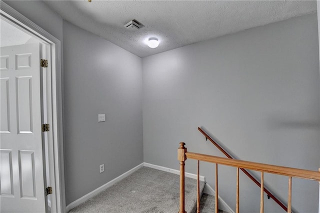 staircase with a textured ceiling and carpet floors