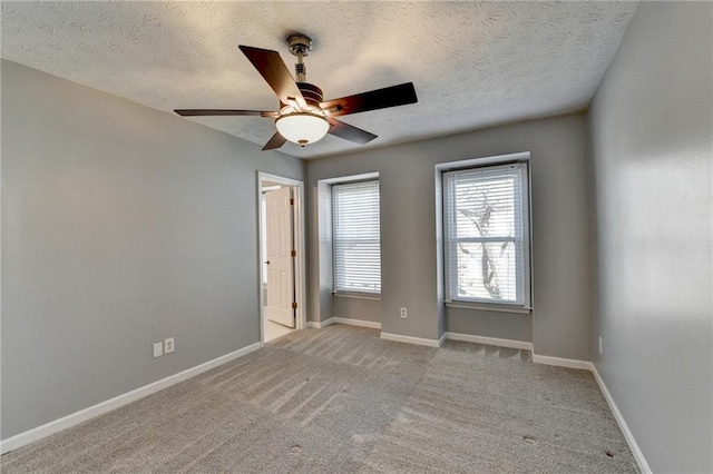 unfurnished room featuring ceiling fan, light colored carpet, and a textured ceiling