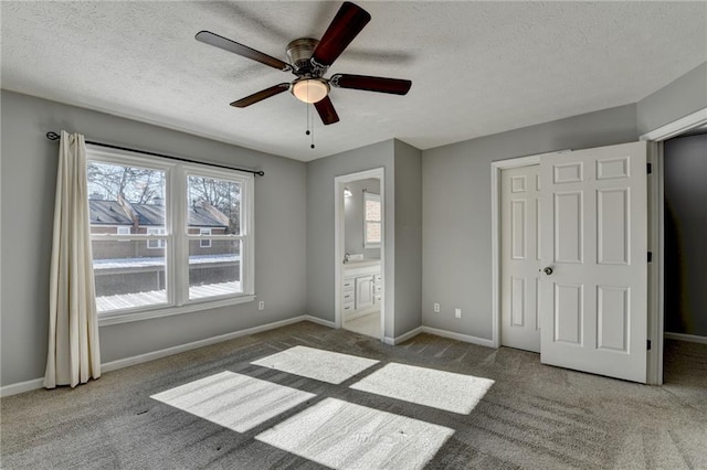 unfurnished bedroom featuring a textured ceiling, ensuite bathroom, ceiling fan, and light colored carpet