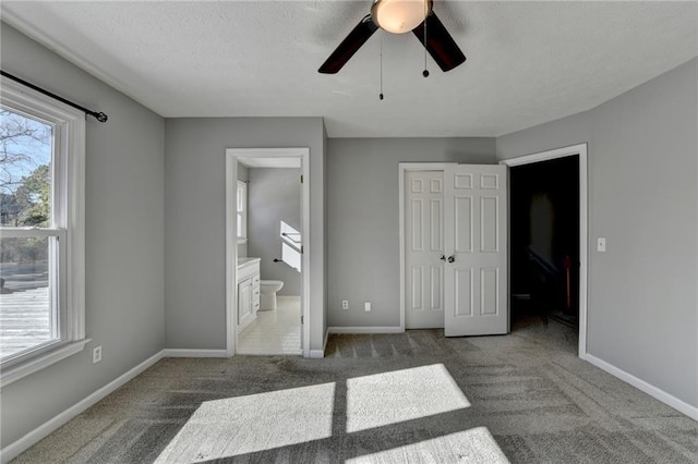 unfurnished bedroom featuring carpet flooring, a closet, ensuite bath, and ceiling fan