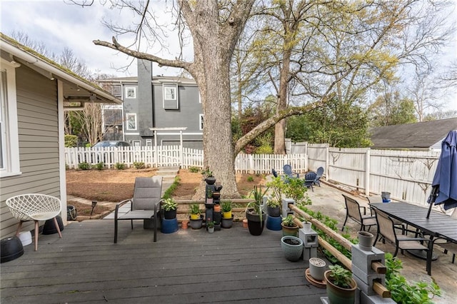 wooden terrace with outdoor dining area and a fenced backyard