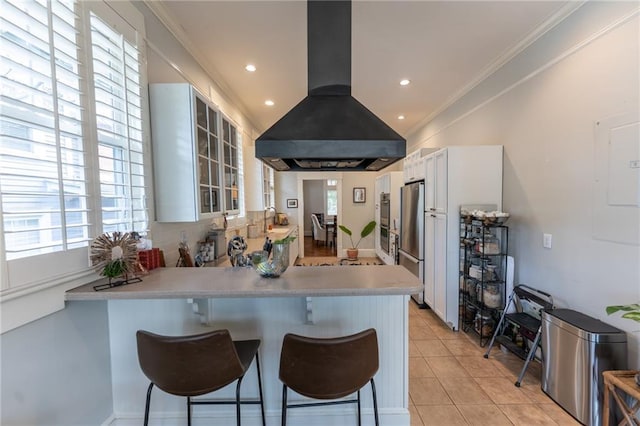 kitchen featuring crown molding, island exhaust hood, freestanding refrigerator, and a kitchen breakfast bar