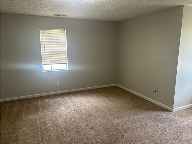 carpeted spare room featuring baseboards and a textured ceiling