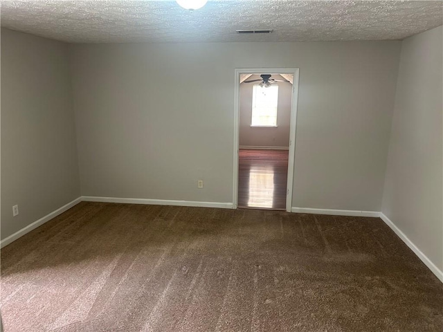 unfurnished room with a ceiling fan, carpet flooring, a textured ceiling, and visible vents
