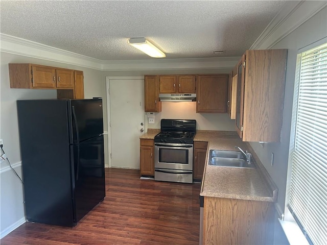 kitchen with a sink, stainless steel gas stove, a textured ceiling, freestanding refrigerator, and under cabinet range hood