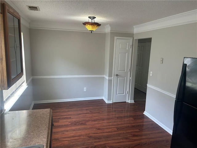 unfurnished dining area with a textured ceiling, visible vents, dark wood-style floors, and ornamental molding