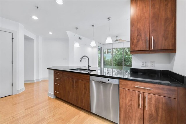 kitchen with hanging light fixtures, stainless steel dishwasher, light hardwood / wood-style flooring, dark stone countertops, and sink