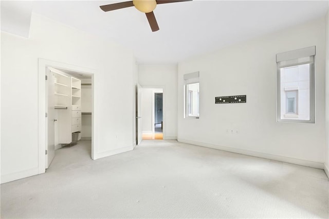 unfurnished bedroom featuring a spacious closet, ceiling fan, a closet, and light colored carpet