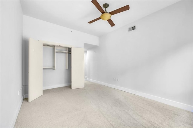 unfurnished bedroom featuring light colored carpet, a closet, and ceiling fan