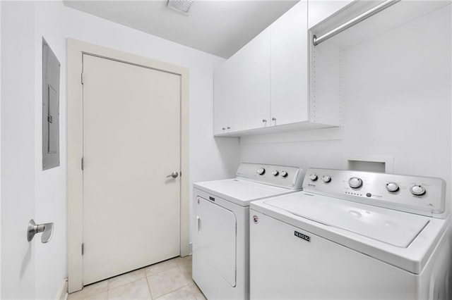 laundry room featuring electric panel, washing machine and dryer, light tile patterned floors, and cabinets