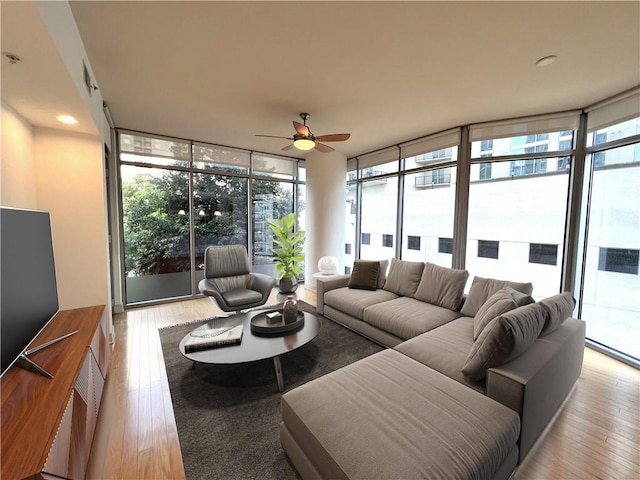 living room with a wealth of natural light, a wall of windows, light wood-type flooring, and ceiling fan