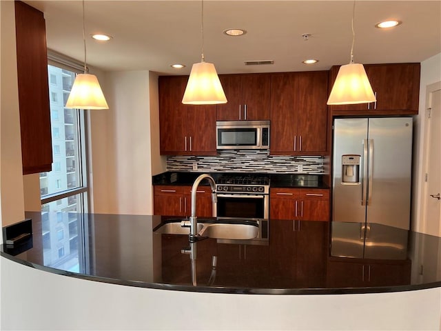 kitchen with sink, hanging light fixtures, stainless steel appliances, and tasteful backsplash