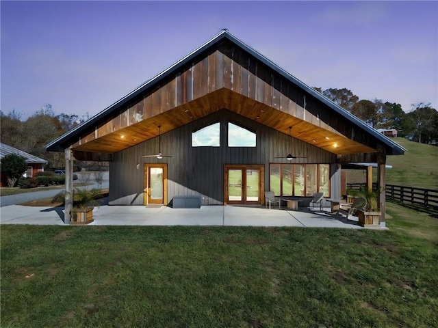 back house at dusk with a yard and a patio