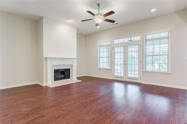 unfurnished living room featuring visible vents, a fireplace with raised hearth, ceiling fan, baseboards, and wood finished floors