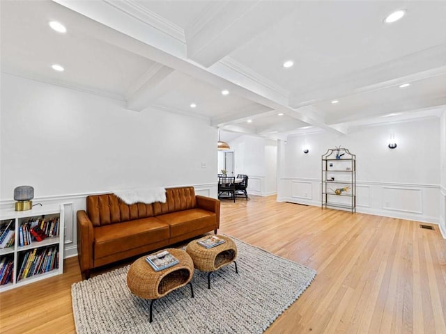 living area with a decorative wall, beam ceiling, and light wood finished floors