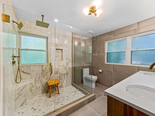 full bath featuring a sink, a stall shower, tile walls, double vanity, and toilet