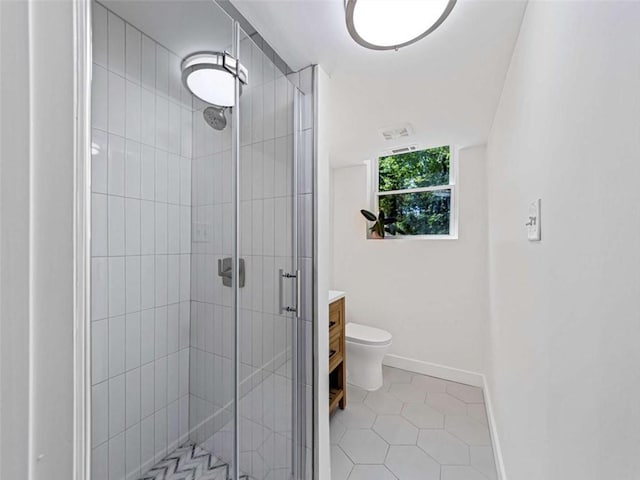 bathroom with tile patterned floors, toilet, vanity, baseboards, and a stall shower