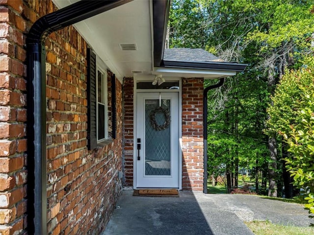 doorway to property with brick siding and visible vents