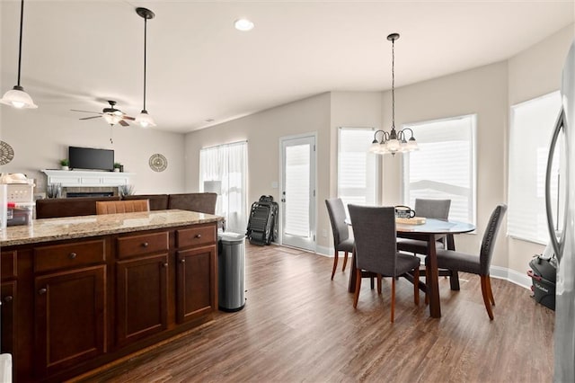 106 Thurman Ct, Jackson, GA 30233 - dining space featuring a fireplace, baseboards, dark wood-style floors, and ceiling fan with notable chandelier