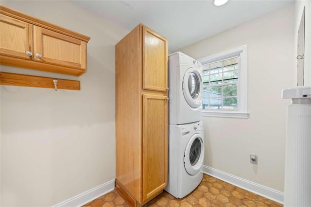 washroom with cabinets and stacked washing maching and dryer