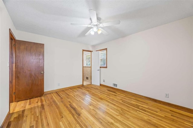 empty room with ceiling fan, a textured ceiling, and light wood-type flooring