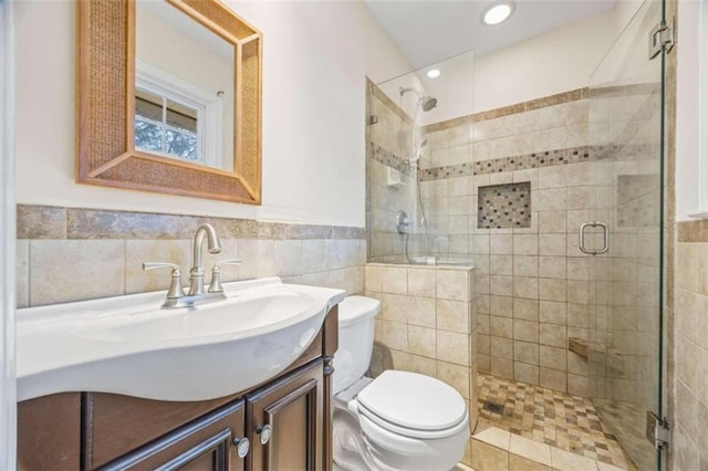 bathroom with vanity, toilet, tile walls, and a shower with shower door