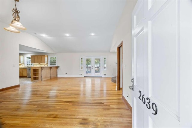 unfurnished living room featuring lofted ceiling, french doors, and light hardwood / wood-style flooring