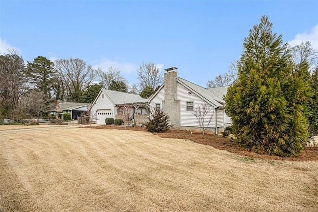 view of side of home featuring a lawn, an attached garage, and a chimney