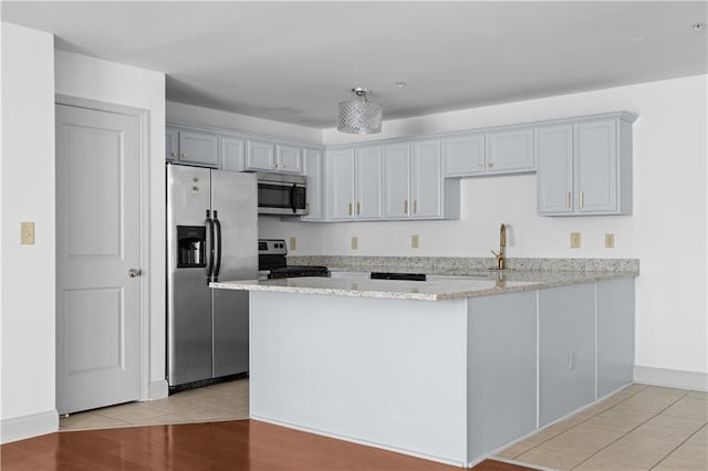 kitchen with light stone countertops, light wood-type flooring, kitchen peninsula, and appliances with stainless steel finishes