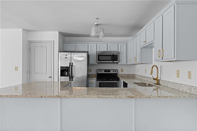 kitchen featuring light stone countertops, stainless steel appliances, kitchen peninsula, and sink