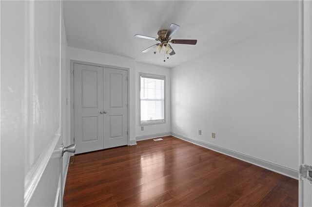 unfurnished bedroom featuring ceiling fan and dark wood-type flooring