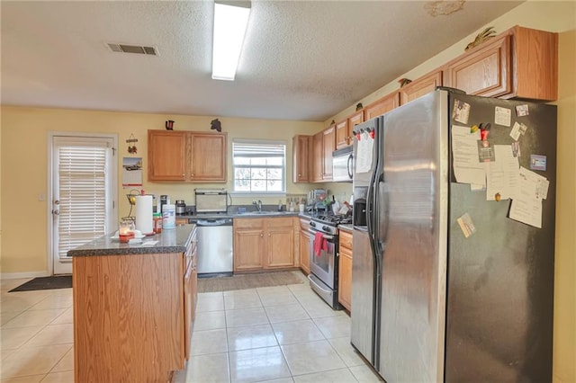 kitchen with appliances with stainless steel finishes, a textured ceiling, light tile patterned floors, and sink