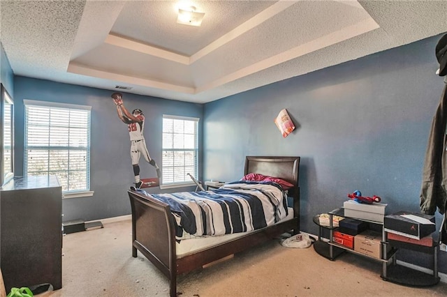 bedroom featuring a textured ceiling, a tray ceiling, and light colored carpet