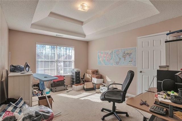 office area featuring carpet, a textured ceiling, and a tray ceiling