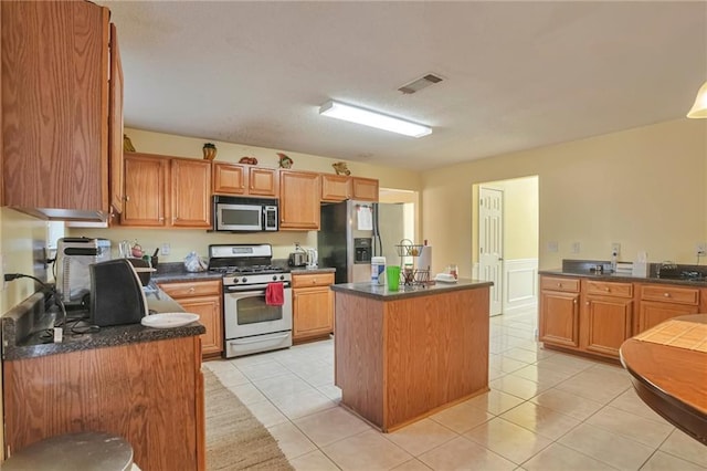 kitchen featuring a kitchen island, light tile patterned floors, and appliances with stainless steel finishes