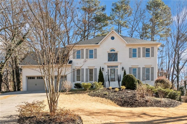 colonial-style house featuring a garage, concrete driveway, and brick siding