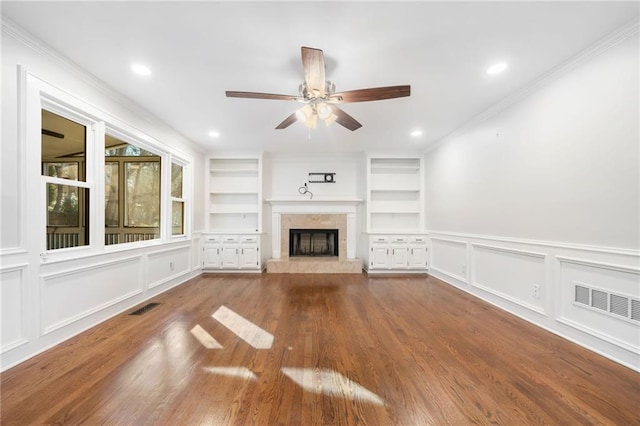 unfurnished living room featuring built in features, visible vents, and a decorative wall