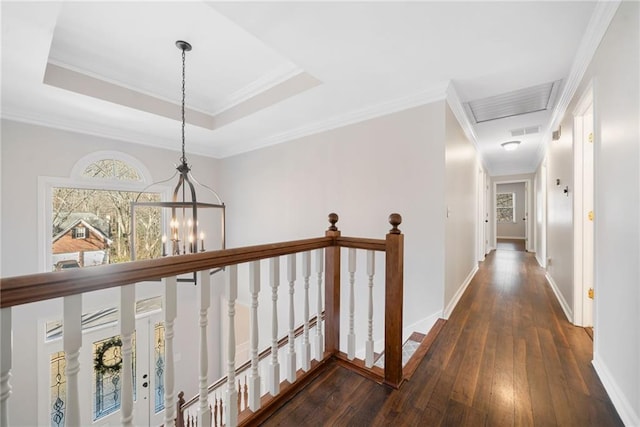 hall featuring crown molding, a raised ceiling, an upstairs landing, a chandelier, and hardwood / wood-style flooring