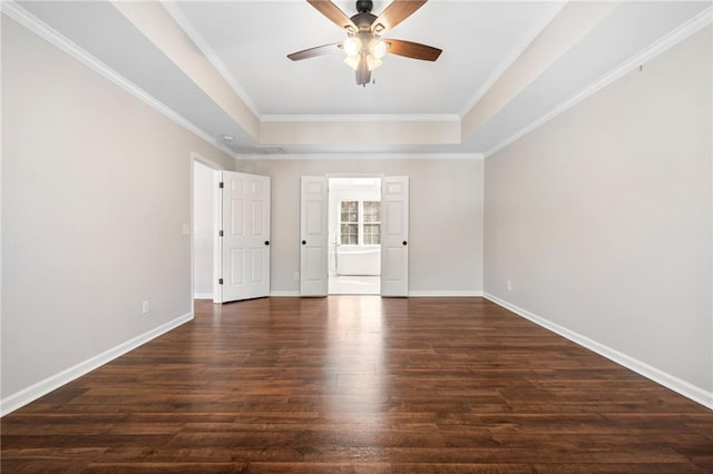 empty room featuring dark wood-style flooring, a raised ceiling, a ceiling fan, ornamental molding, and baseboards