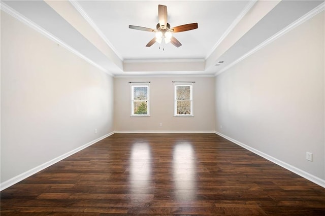 empty room featuring crown molding, dark wood-type flooring, a raised ceiling, and baseboards