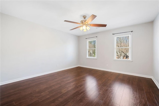 empty room with ceiling fan, baseboards, and dark wood-type flooring