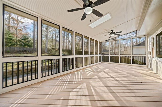 unfurnished sunroom with ceiling fan and lofted ceiling with skylight