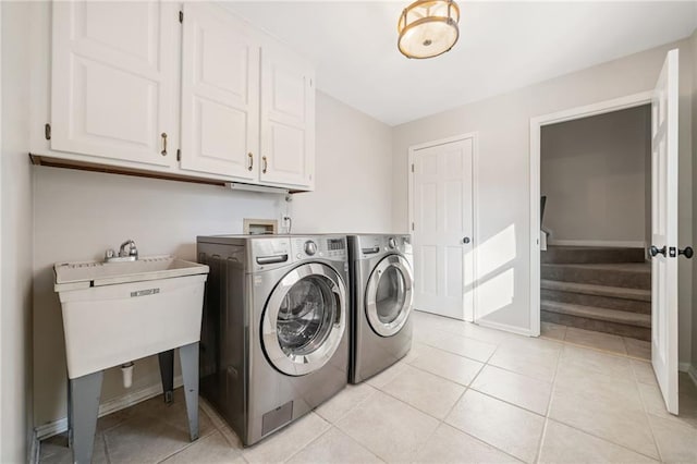 washroom with washing machine and dryer, cabinet space, baseboards, and light tile patterned floors