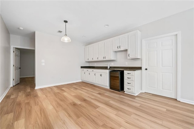 kitchen with visible vents, dark countertops, wine cooler, light wood-type flooring, and white cabinetry