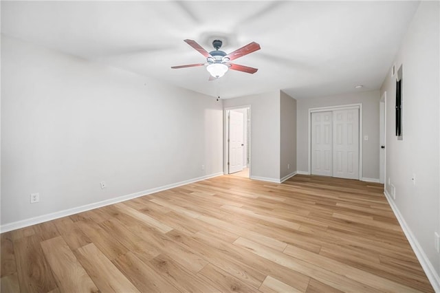 unfurnished bedroom with ceiling fan, a closet, light wood-type flooring, and baseboards