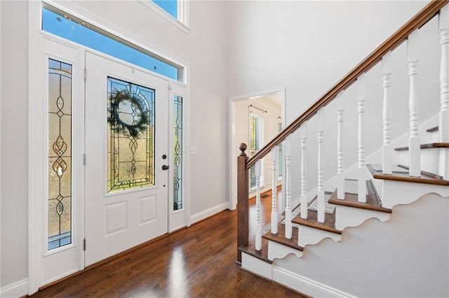 entrance foyer with stairway, a towering ceiling, baseboards, and wood finished floors